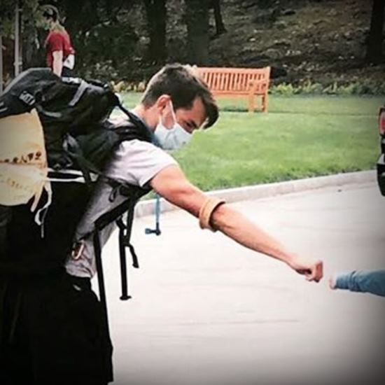 Student in backpack bumping fists with a child