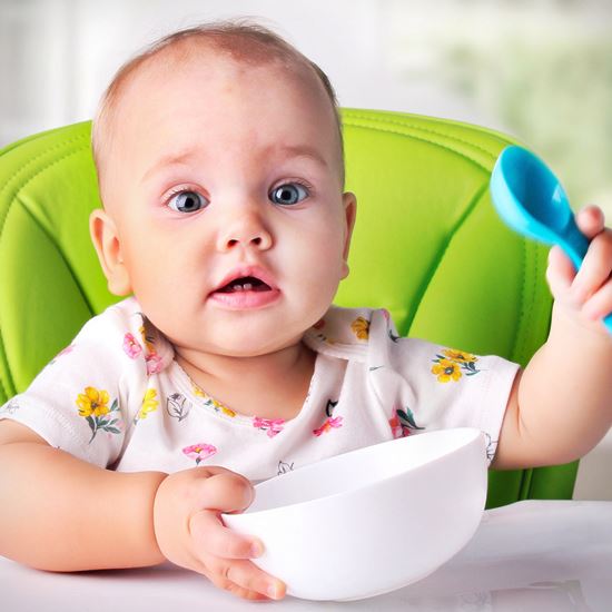 Baby with plastic bowl and spoon
